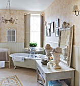 SARAH BAKERS HOUSE  THE OLD VICARAGE: BATHROOM WITH BATH  SHELVED CONSOLE  VINTAGE MIRROR AND SHELLS DISPLAYED IN VINTAGE GARDEN URNS.