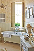 SARAH BAKERS HOUSE  THE OLD VICARAGE: BATHROOM WITH ROLL TOP BATH  SHELVED CONSOLE  VINTAGE MIRROR AND SHELLS DISPLAYED IN VINTAGE GARDEN URNS.