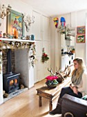 SARAH BAKERS HOUSE  THE OLD VICARAGE: SARAH BAKERS DAUGHTER SITS IN THE FAMILY ROOM WITH LOG FIRE
