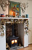 SARAH BAKERS HOUSE  THE OLD VICARAGE: THE FAMILY ROOM: LOG BURNING STOVE WITH DEERS HEAD WOOD BARK WALL DECORATION