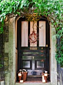 SARAH BAKERS HOUSE  THE OLD VICARAGE: FRONT DOOR DRESSED WITH MISTLETOE BALL AND BERRIED WREATH.PLANTERS AND LANTERNS SET WITH CHURCH CANDLES WELCOME VISITORS.