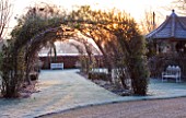 THE MANOR HOUSE  STEVINGTON  BEDFORDSHIRE. DESIGNER: KATHY BROWN - THE WISTERIA WALK PERGOLA AT DAWN IN WINTER - VIEW ALONG TO SEAT