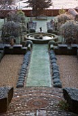 THE MANOR HOUSE  STEVINGTON  BEDFORDSHIRE. DESIGNER: KATHY BROWN - THE FRENCH PARTERRES AT DAWN - VIEW ALONG THE FORMAL GARDEN WITH CLIPPED YEW HEDGES