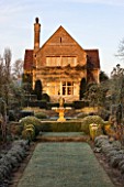 THE MANOR HOUSE  STEVINGTON  BEDFORDSHIRE. DESIGNER: KATHY BROWN - THE FRENCH PARTERRES AT DAWN - VIEW ALONG THE FORMAL GARDEN WITH CLIPPED YEW HEDGES TO THE MANOR HOUSE