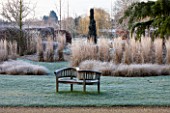 THE MANOR HOUSE  STEVINGTON  BEDFORDSHIRE. DESIGNER: KATHY BROWN - THE MONET BORDERS AT DAWN WITH FROST AND WOODEN BENCH ON LAWN