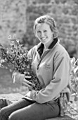 HERM ISLAND  CHANNEL ISLANDS - BLACK AND WHITE IMAGE OF ASSISTANT ISLAND GARDENER ROSIE WHEELER WITH BOUQUET OF FLOWERS IN PINK - GLADIOLUS COMMUNIS BYZANTINUS AND RED CAMPION