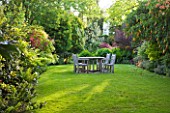 GRANGE COURT  GUERNSEY: WOODEN TABLE AND CHAIRS ON THE LAWN WITH BRUGMANSIA SANGUINEA IN FLOWER ON THE RIGHT