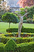 GRANGE COURT  GUERNSEY: SCULPTURE WELCOME THE NEW YEAR BY EVERARD MEYNELL IN BOX BEDS WITH LAWN BEHIND