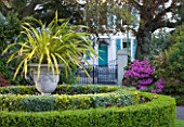 GRANGE COURT  GUERNSEY: VIEW PAST URN WITH PHORMIUM AND CIRCULAR BOX BED TO GATES AND HOUSE OPPOSITE