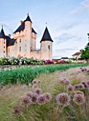 CHATEAU DU RIVAU  LOIRE VALLEY  FRANCE: THE CHATEAU IN EVENING LIGHT SEEN FROM THE RAPUNZEL GARDEN WITHALLIUM GIGANTEUM AND STIPA TENUIFOLIA
