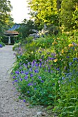 NYMANS  SUSSEX. THE NATIONAL TRUST: BLUE GERANIUMS AND ALSTROEMERIAS IN THE HERBACEOUS BORDER  JUNE  EVENING LIGHT