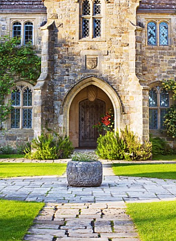 NYMANS__SUSSEX_THE_NATIONAL_TRUST_THE_FORECOURT_IN_EVENING_LIGHT_WITH_STONE_PATHS_AND_STONE_CONTAINE