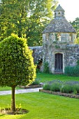 NYMANS  SUSSEX. THE NATIONAL TRUST: THE FORECOURT IN EVENING LIGHT WITH STONE PATHS  DOVECOTE AND STANDARD BAY TREE  JUNE  EVENING LIGHT