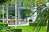 THE GLASS HOUSE  PETERSHAM. ARCHITECTS TERRY FARRELL PARTNERS. GARDEN DESIGN BY SALLIS CHANDLER: VIEW ACROSS LAWN TO LIMESTONE PATIO WITH TABLE AND CHAIRS  BETULA JACQUEMONTII