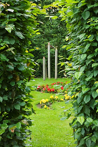 OLD_THATCH__BERKSHIRE_VIEW_THROUGH_HORNBEAM_HEDGE_TO_THE_PENCIL_GARDEN_WITH_WOODEN_PENCILS_AND_BEGON
