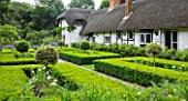 OLD THATCH  BERKSHIRE: THE THATCHED COTTAGE SEEN FROM THE FORMAL GARDEN OF CLIPPED BOX HEDGES AND LOLLIPOPS OF VARIEGATED YEW