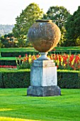 THE NATIONAL TRUST: CLIVEDEN  BUCKINGHAMSHIRE: THE PARTERRE IN EVENING LIGHT WITH LARGE STONE URN   YELLOW AND RED GLADIOLI AND VIEW TO THE WOODLAND BEYOND - AUGUST