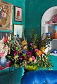 VELVET ECCENTRIC: NEW COUNTRY LOOK - GREEN VINTAGE JARDINIERE WITH FAUX FLOWERS AND PHEASANT FEATHERS  PERSIAN GREEN GLAZED WALLS  FLORAL PAINTINGS AND BLUE VELVET CHAIR