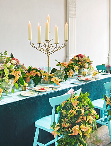 DESIGN_BY_REBEL_REBEL_DINING_TABLE_WITH_BLUE_CHAIRS_DECORATED_WITH_CANDLES_STAND_AND_POINSETTIA_CHRI