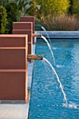 AFRICAN GARDEN  PROVENCE  FRANCE: DESIGNER DOMINIQUE LAFOURCADE: TERRACOTTA COLOURED WATER FOUNTAINS SPURT INTO THE SWIMMING POOL
