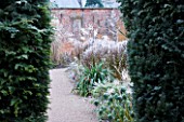 HAMPTON COURT CASTLE AND GARDENS  HEREFORDSHIRE: THE WALLED GARDEN IN FROST - VIEW THROUGH YEW HEDGES TO BORDER