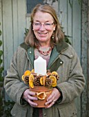 THE GARDEN AND PLANT COMPANY  HATHEROP  GLOUCESTERSHIRE: PATI WESTON WITH CONE AND DRIED ORANGE CANDLE TABLE CENTREPIECE APPROPRIATELY SITTING IN A PLANT POT