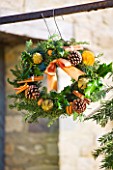 THE GARDEN AND PLANT COMPANY  HATHEROP  GLOUCESTERSHIRE: FIR WREATH DECORATED WITH HOLLY ROSEMARY  DRIED ORANGES  PINE CONES  CINNAMON STICKS AND CHILLI PEPPERS