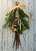 THE GARDEN AND PLANT COMPANY  HATHEROP  GLOUCESTERSHIRE: NATURAL HAND-TIE FIR SPRIGS  LONG PHEASANT FEATHERS  CORN EARS  ORANGES  CINNAMON AND PINE CONES