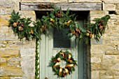THE GARDEN AND PLANT COMPANY  HATHEROP  GLOUCESTERSHIRE: FIR GARLAND AND DOOR WREATH DRESSED WITH PINE CONES  DRIED ORANGES AND LIMES  CINNAMON STICKS  CHILLIES  BRONZED BAUBLES.
