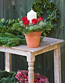 THE GARDEN AND PLANT COMPANY  HATHEROP  GLOUCESTERSHIRE: FESTIVE FOLIAGE AND FLOWERS; FIR   HOLLY GARLANDS  PLANT POT CANDLE TABLE CENTREPIECE PINE  ERYNGIUM AND RED ROSES