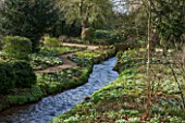 LITTLE PONTON HALL  LINCOLNSHIRE: THE STREAM WITH GRAVEL PATH SURROUNDED BY SNOWDROPS AND ACONITES