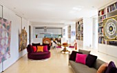 SHELLEY VON STRUNCKEL APARTMENT  LONDON: THE MAIN LIVING AREA WITH KITCHEN AT REAR AND BURGUNDY VELVET CIRCULAR SEAT