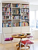 SHELLEY VON STRUNCKEL APARTMENT  LONDON: WOODEN CIRCULAR TABLE AND PHILIPPE STARCK CHAIRS  WITH BOOKSHELF BEHIND