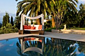 DESIGNER JAMES BASSON, SCAPE DESIGN, FRANCE: SKY REFLECTED IN SWIMMING POOL WITH CANOPY OVER SUN LOUNGER- WATER, REFLECTION, REFLECTIONS, PALM TREE, RELAX, RELAXING