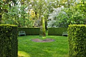 DODDINGTON PLACE GARDENS  KENT: BENCHES AND BLOSSOM IN THE SPRING GARDEN WITH MIRRORED OBELISK BY DAVID HARBOUR