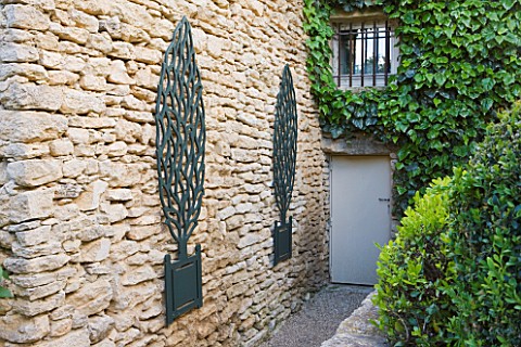GARDEN_IN_LUBERON__FRANCE__DESIGNED_BY_MICHEL_SEMINI_WOODEN_TROMPE_LOEIL_TREES_IN_CONTAINERS_ON_WALL