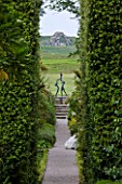 TRESCO ABBEY GARDEN  TRESCO   ISLES OF SCILLY: VIEW DOWN THE NEPTUNE STEPS PAST HEDGES OF QUERCUS ILEX HEDGES TO SCULPTURE - TRESCO CHILDREN BY DAVID WYNNE