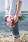 THE ISLES OF SCILLY: SCILLY FLOWERS - FRESHLY PICKED SCENTED PINKS BY THE SEA  HELD BY STEPH HILL