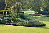 GLYNDEBOURNE, EAST SUSSEX: BORDER BESIDE THE LAWN WITH EREMURUS, ALLIUMS AND BERBERIS - SUMMER, HERBACEOUS, COUNTRY GARDEN