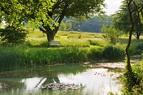 GLYNDEBOURNE_EAST_SUSSEX_VIEW_ACROSS_LAKE_TO_MEADOW_AND_WOODEN_SEAT__BENCH__WATER_POOL_TRANQUIL_PEAC