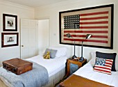RICHARD CARNILL HOUSE  NOTTINGHAMSHIRE: TWIN GUEST ROOM. 1950S AMERICAN FLAG (48 STARS)  WOOD AND PUNCHED ZINC FRONTED CUPBOARD  LAMPS BY RALPH LAUREN HOME