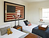 RICHARD CARNILL HOUSE  NOTTINGHAMSHIRE: TWIN GUEST ROOM. 1950S AMERICAN FLAG (48 STARS)  WOOD AND PUNCHED ZINC FRONTED CUPBOARD  LAMPS BY RALPH LAUREN HOME
