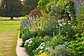 BROUGHTON CASTLE, OXFORDSHIRE: BLUE, YELLOW AND WHITE PLANTING IN THE BORDER BESIDE THE CASTLE WALL. COUNTRY GARDEN, SUMMER, FLOWERS, HERBACEOUS