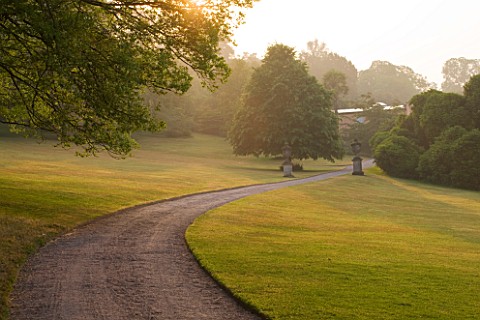 KILLERTON__DEVON_THE_NATIONAL_TRUST__PATH_THROUGH_LAWNS_AND_TREES_IN_THE_GARDEN_WITH_THE_WEST_FRONT_