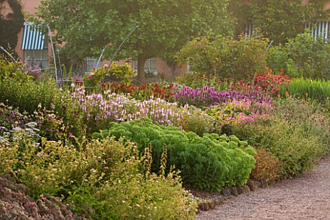 KILLERTON__DEVON_THE_NATIONAL_TRUST_HERBACEOUS_BORDER_WITH_WEST_FRONT_OF_HOUSE_BEHIND