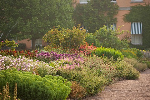 KILLERTON__DEVON_THE_NATIONAL_TRUST_HERBACEOUS_GARDEN_WITH_WEST_FRONT_OF_THE_HOUSE_IN_BACKGROUND__MO