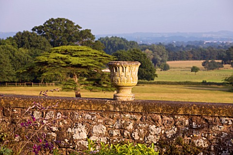 KILLERTON__DEVON_THE_NATIONAL_TRUST_HERBACEOUS_GARDEN__URN_ON_TOP_OF_WALL_WITH_PARKLAND_BEYOND__EVEN