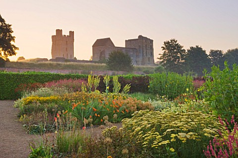 HELMSLEY_WALLED_GARDEN__YORKSHIRE_HELMSLEY_CASTLE_SEEN_AT_DAWN_WITH_HERBACEOUS_BORDER_IN_THE_FORGROU