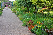 SLEDMERE HOUSE GARDEN, YORKSHIRE: PATH THROUGH EXOTIC BORDERS WITH ANNUALS AND TENDER AND HARDY PERENNIALS - MUSA ENSETE, ANTIRRHINUM CANARYBIRD, SUNDIAL, FOCAL POINT, COUNTRY