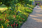 SLEDMERE HOUSE GARDEN, YORKSHIRE: PATH THROUGH EXOTIC BORDERS WITH ANNUALS AND TENDER AND HARDY PERENNIALS - MUSA ENSETE, ANTIRRHINUM CANARYBIRD, SUNDIAL, FOCAL POINT, COUNTRY